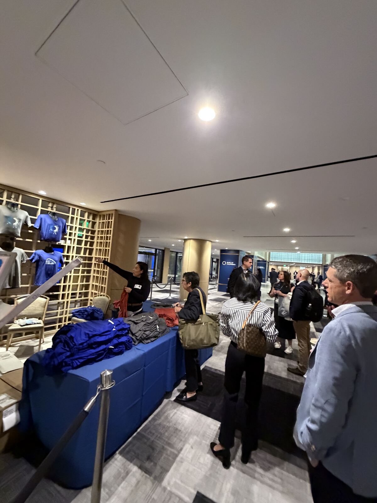 Corporate professionals examining decorated t-shirts and printed apparel at a business event