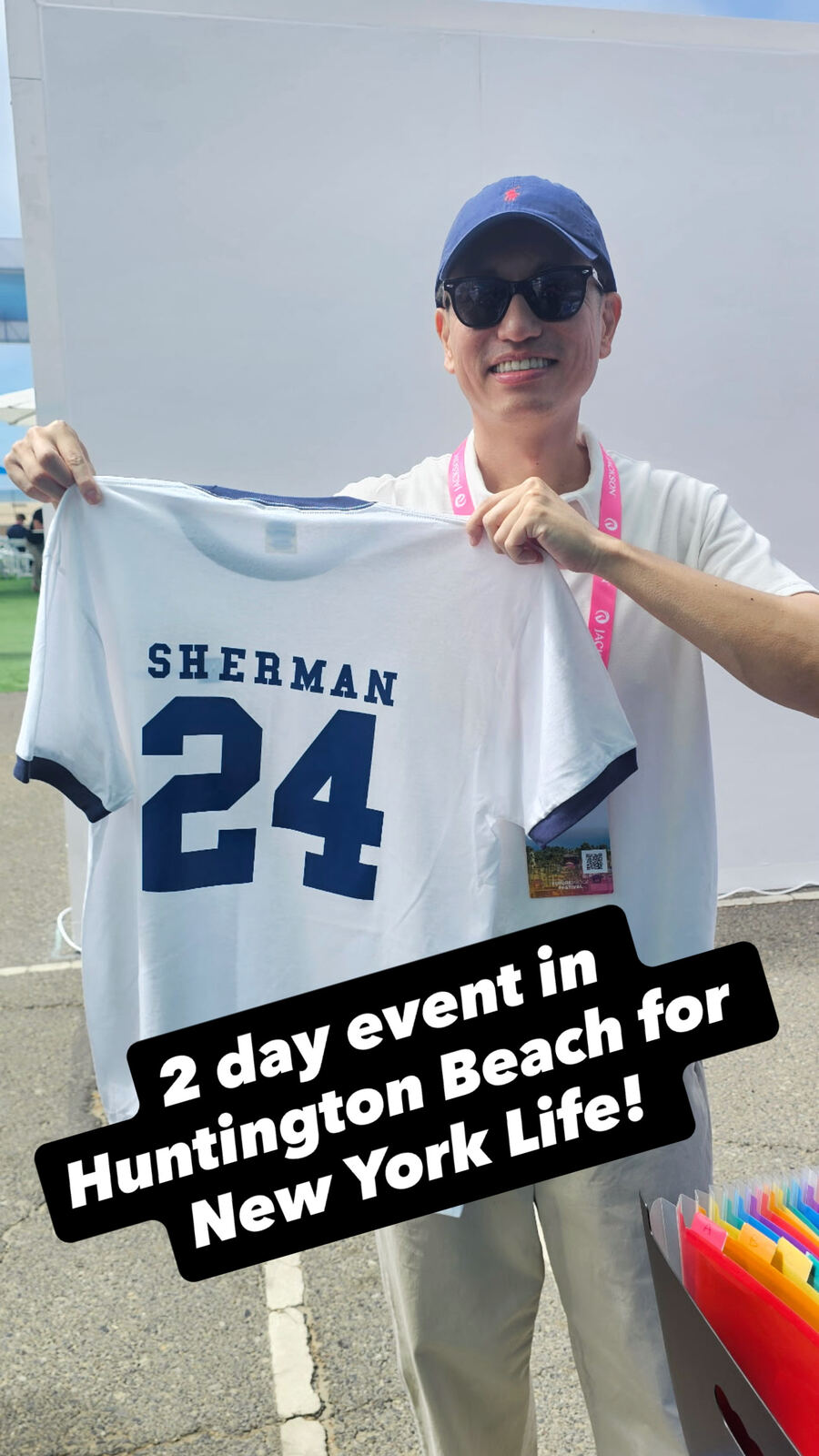 Man proudly displaying a custom Sherman #24 baseball jersey at a beach event with event branding